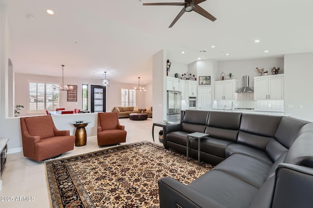 living area featuring recessed lighting, ceiling fan with notable chandelier, lofted ceiling, and baseboards