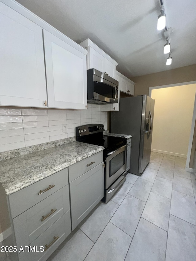 kitchen featuring light tile patterned floors, gray cabinetry, white cabinets, appliances with stainless steel finishes, and decorative backsplash