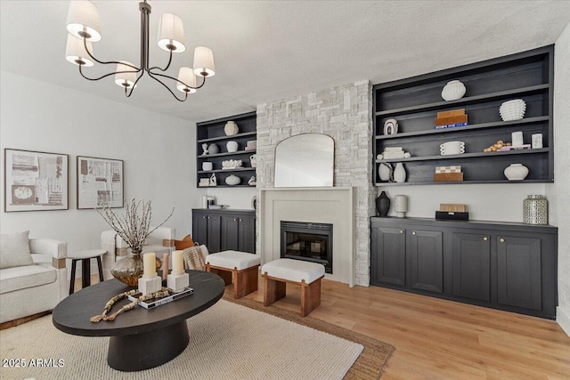 living room featuring light hardwood / wood-style flooring, a chandelier, a textured ceiling, and built in features