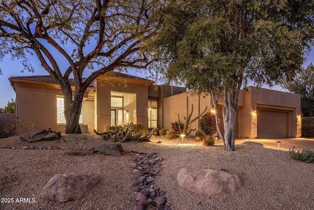 adobe home featuring a garage and stucco siding