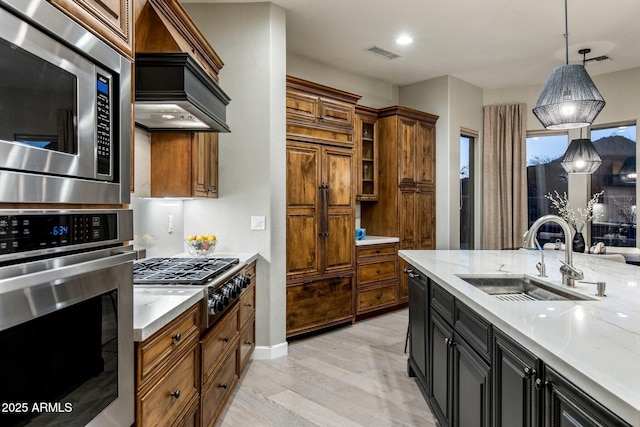 kitchen with visible vents, brown cabinetry, a sink, and built in appliances