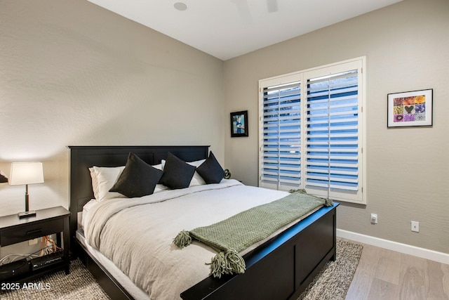 bedroom featuring light wood-style floors, baseboards, and a ceiling fan