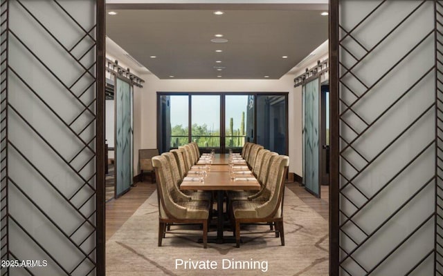 dining room featuring a barn door, light wood-style flooring, and recessed lighting