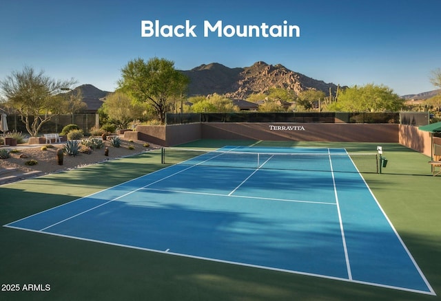 view of tennis court featuring fence and a mountain view