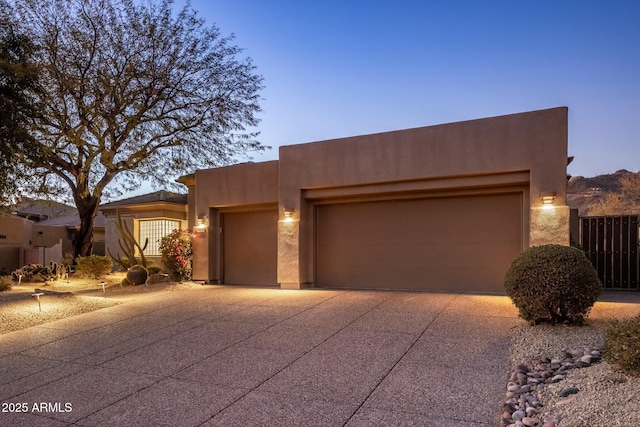 southwest-style home featuring concrete driveway, an attached garage, and stucco siding