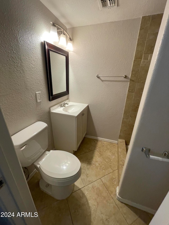 bathroom with tile flooring, vanity, toilet, and a textured ceiling