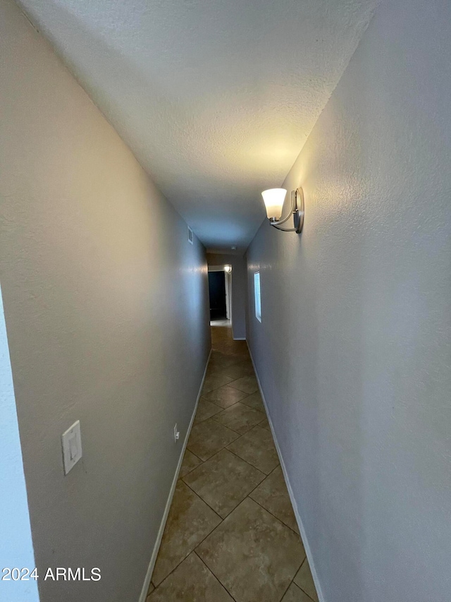 corridor featuring tile floors and a textured ceiling