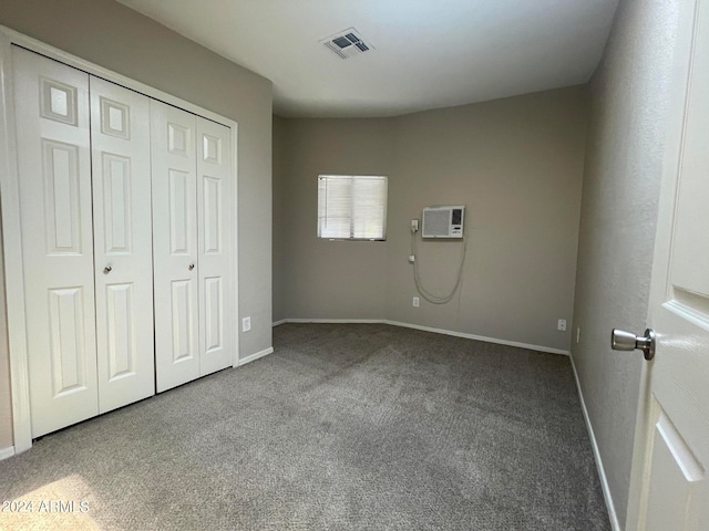 unfurnished bedroom featuring a closet, carpet, and an AC wall unit