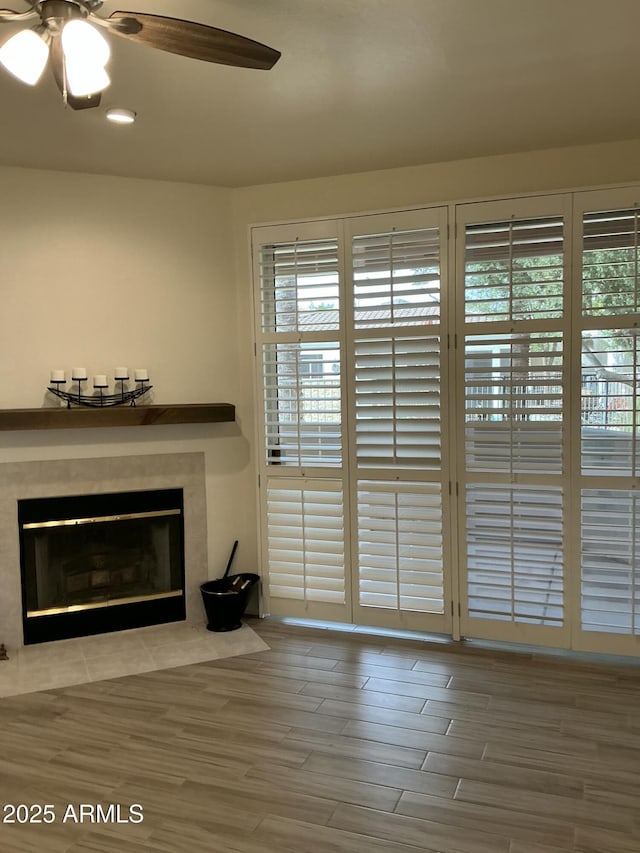 unfurnished living room featuring a fireplace with flush hearth, a healthy amount of sunlight, and a ceiling fan