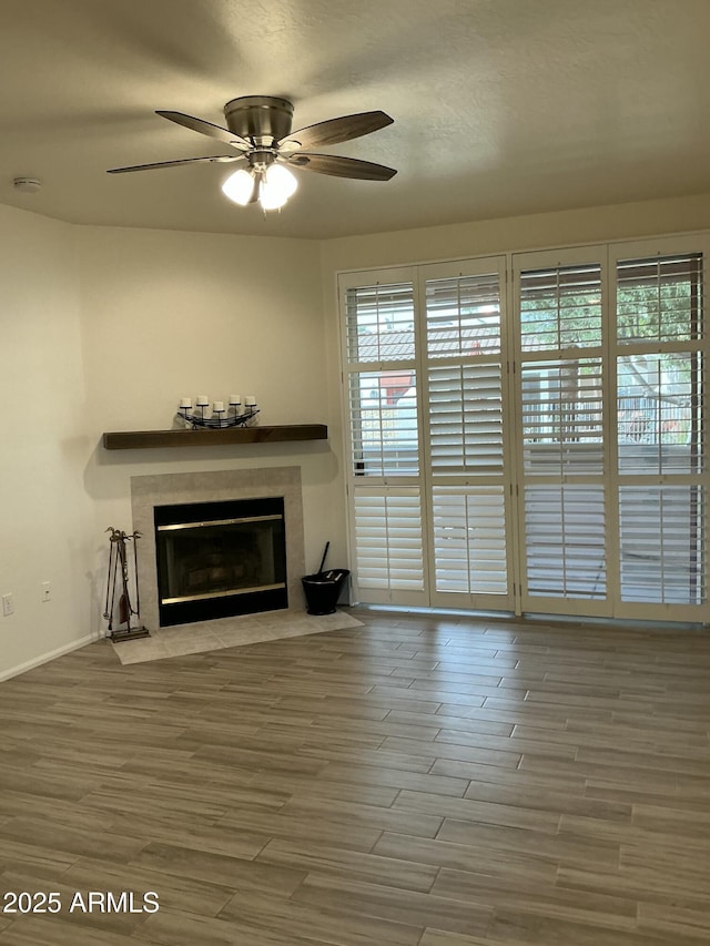 unfurnished living room with a textured ceiling, a fireplace, wood finished floors, and a ceiling fan