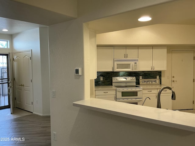 kitchen featuring white appliances, white cabinetry, light countertops, and decorative backsplash