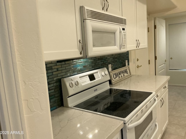 kitchen featuring white appliances, white cabinets, backsplash, and light stone countertops