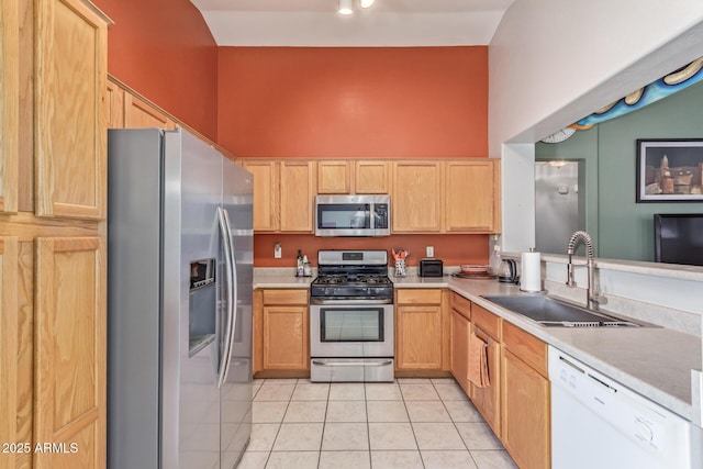 kitchen featuring light countertops, light brown cabinets, light tile patterned floors, a sink, and appliances with stainless steel finishes