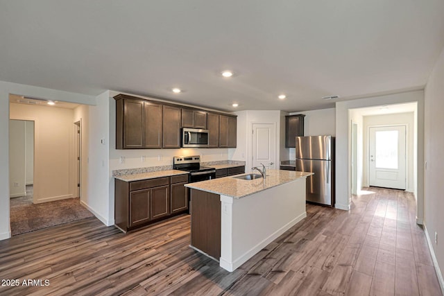 kitchen featuring dark brown cabinetry, visible vents, an island with sink, stainless steel appliances, and a sink