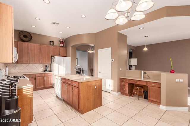 kitchen featuring light tile patterned flooring, sink, tasteful backsplash, decorative light fixtures, and a kitchen island with sink