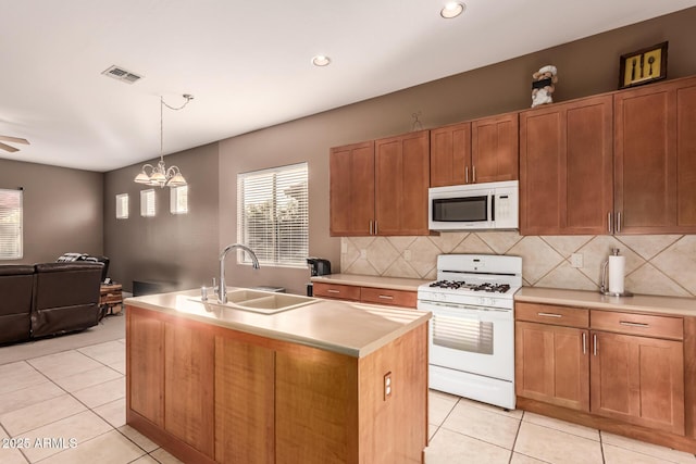 kitchen with sink, light tile patterned floors, white appliances, a kitchen island with sink, and backsplash