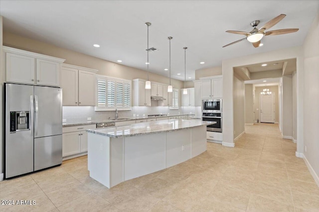 kitchen with sink, appliances with stainless steel finishes, light stone countertops, white cabinets, and a kitchen island