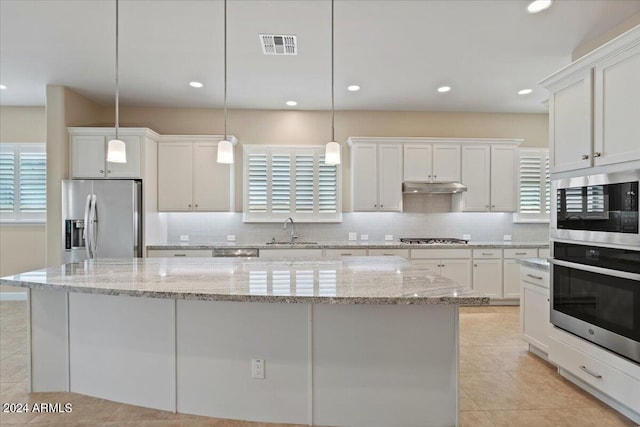 kitchen featuring pendant lighting, appliances with stainless steel finishes, a center island, and sink