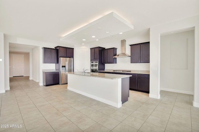 kitchen with light tile patterned floors, stainless steel appliances, dark brown cabinetry, a center island with sink, and wall chimney exhaust hood