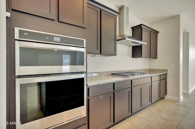 kitchen featuring light tile patterned floors, stainless steel appliances, and wall chimney exhaust hood