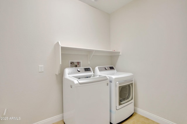 clothes washing area with washer and dryer and light tile patterned floors