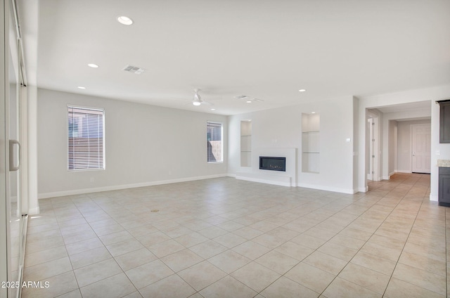 unfurnished living room with built in shelves, ceiling fan, a healthy amount of sunlight, and light tile patterned flooring