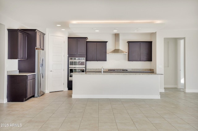 kitchen with a kitchen island with sink, wall chimney range hood, stainless steel appliances, and light stone countertops