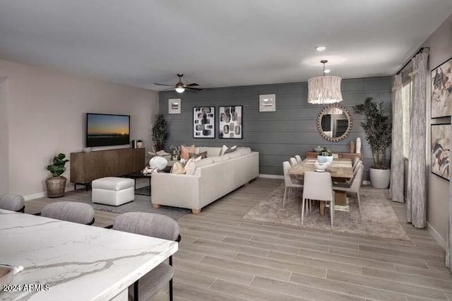 living room with ceiling fan with notable chandelier and light wood-type flooring