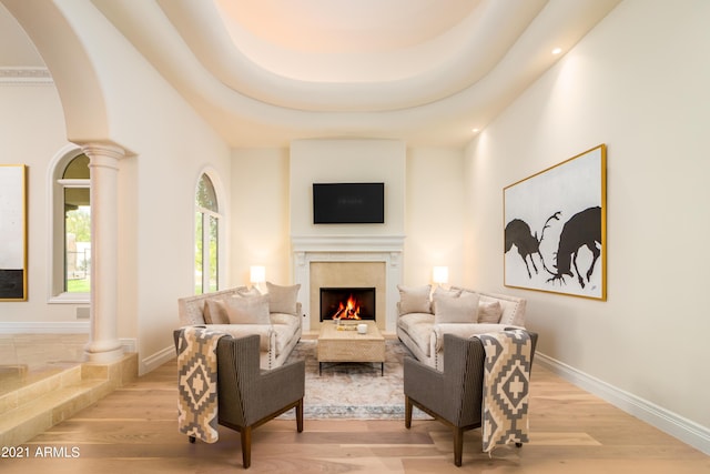 10754 E Laurel Ln, Scottsdale, AZ 85259 - living room with a lit fireplace, light wood-type flooring, ornate columns, arched walkways, and recessed lighting