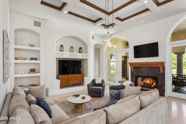 10754 E Laurel Ln, Scottsdale, AZ 85259 - living area featuring built in shelves, coffered ceiling, beamed ceiling, a fireplace, and arched walkways