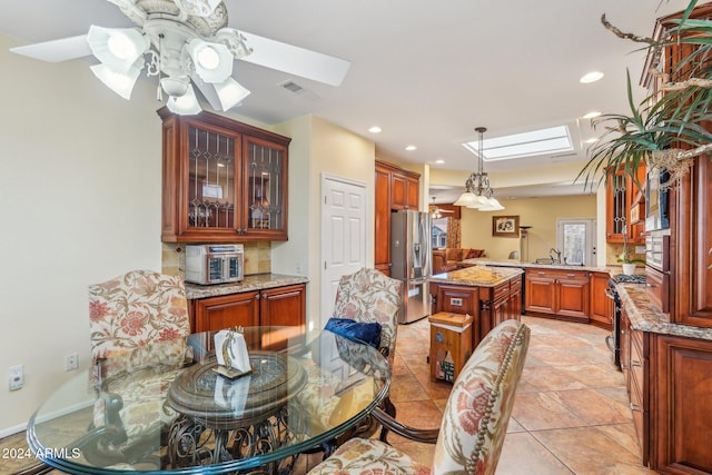 dining area with ceiling fan, light tile patterned floors, sink, and a skylight