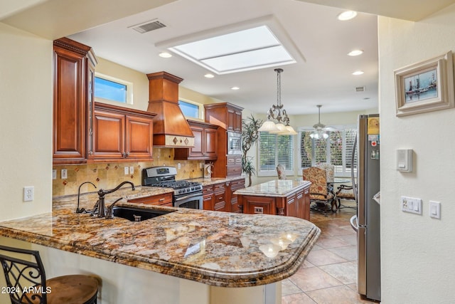 kitchen with a skylight, sink, stainless steel appliances, kitchen peninsula, and a kitchen island