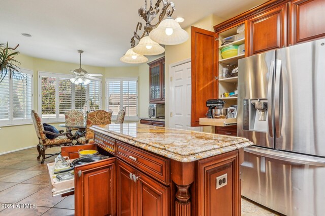 kitchen featuring pendant lighting, stainless steel refrigerator with ice dispenser, ceiling fan, a kitchen island, and light stone counters