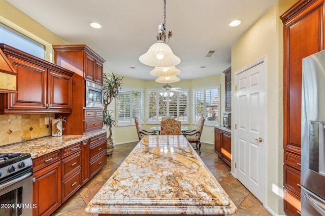 kitchen featuring light stone countertops, a center island, decorative light fixtures, and appliances with stainless steel finishes