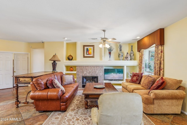 living room with built in shelves, ceiling fan, and a tiled fireplace