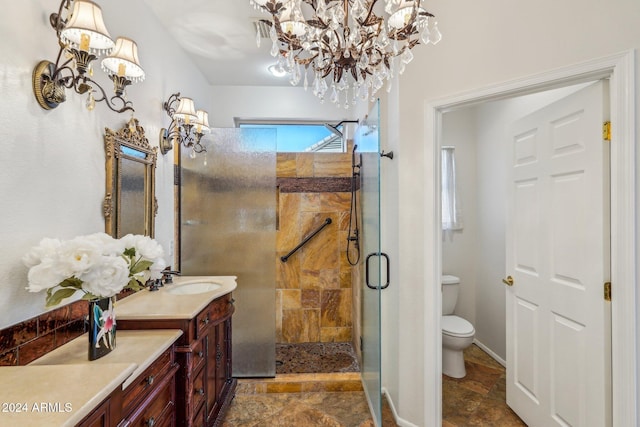 bathroom featuring vanity, toilet, a shower with door, and a notable chandelier