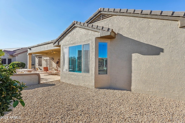 rear view of property with ceiling fan and a patio area