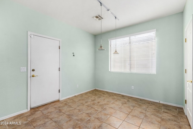 spare room featuring rail lighting