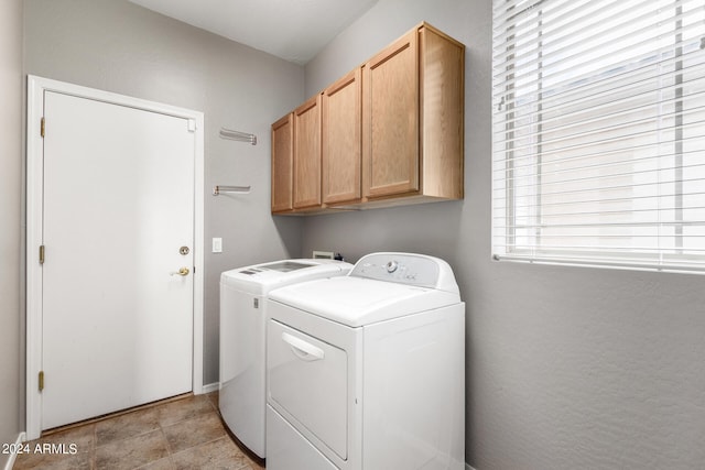 laundry area featuring washing machine and clothes dryer, cabinets, and plenty of natural light