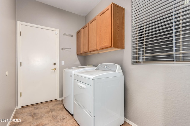 washroom featuring washing machine and clothes dryer and cabinets