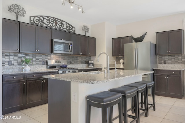 kitchen with sink, dark brown cabinetry, an island with sink, and appliances with stainless steel finishes