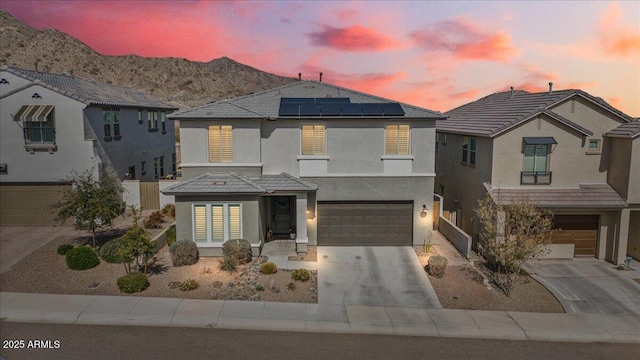 view of front of property featuring solar panels, a mountain view, a tiled roof, and stucco siding