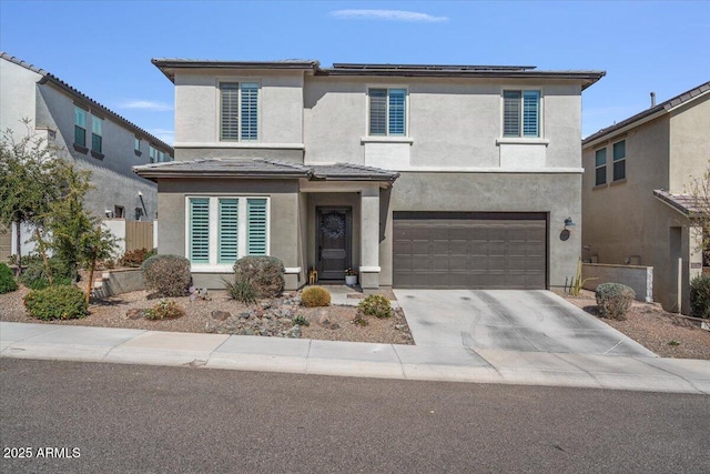 view of front facade with driveway, an attached garage, solar panels, and stucco siding