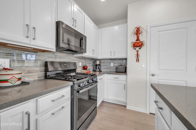 kitchen featuring white cabinets, decorative backsplash, dark stone countertops, and stainless steel appliances