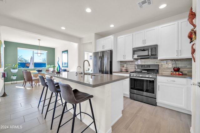 kitchen featuring white cabinetry, sink, a center island with sink, and appliances with stainless steel finishes