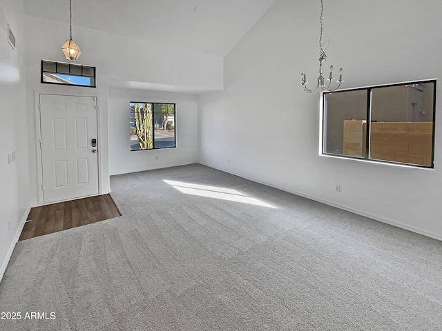 entrance foyer featuring carpet floors, high vaulted ceiling, and an inviting chandelier