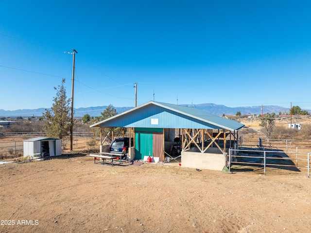 view of outbuilding with a carport, a mountain view, and an outdoor structure