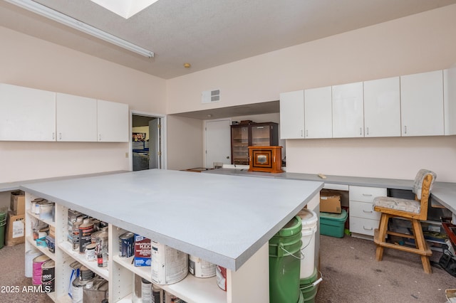 kitchen with visible vents, light carpet, open shelves, white cabinetry, and light countertops