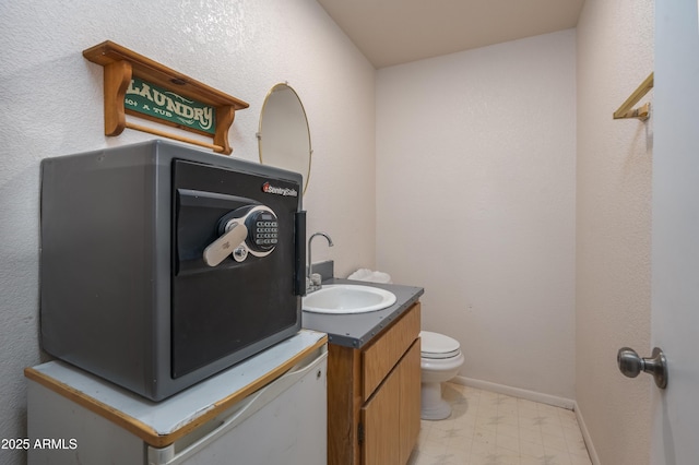 half bath featuring tile patterned floors, baseboards, toilet, and vanity