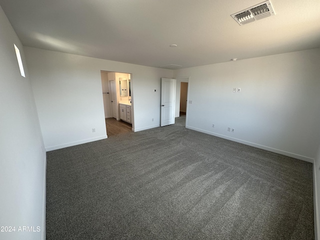 unfurnished bedroom with connected bathroom and dark carpet